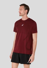 Marmoreret atletisk T-shirt med rund halsudskæring og korte ærmer, prydet med et diskret designmønster og et lille logo på brystet.