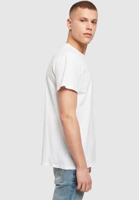 Hvit bomulls T-skjorte med korte ermer, klassisk rund hals design og avslappet passform. Båret med lyseblå jeans.