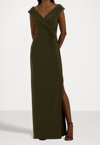 Olive green, sleeveless maxi dress with off-the-shoulder design, knot detail at waist, and side slit. Made of smooth, stretchy fabric.