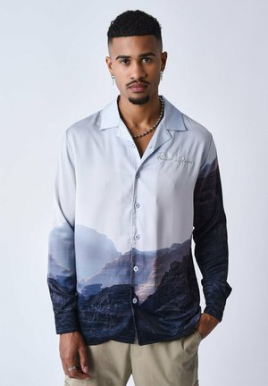 Camicia button-up con stampa paesaggistica di montagne e valli nei toni del grigio e blu scuro. Finitura in satin, maniche lunghe, colletto classico.