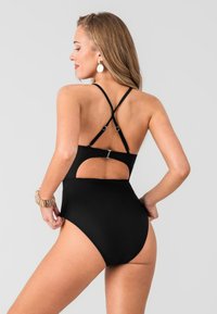 Maillot de bain une pièce noir avec un dos décolleté, des bretelles croisées et une accroche métallique. Tissu lisse et extensible avec une conception taille haute.
