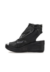 Czarne skórzane sandały na koturnie z odkrytą palcą, zwisającym wzorem, wysokością sięgającą do kostki oraz teksturowaną platformą z srebrnymi akcentami.