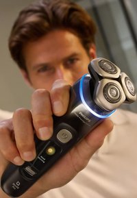 Rasoi Philips 9000 Prestige Ultra con tre testine da barba circolari in acciaio inossidabile, corpo nero, luce LED blu e pulsanti di controllo.