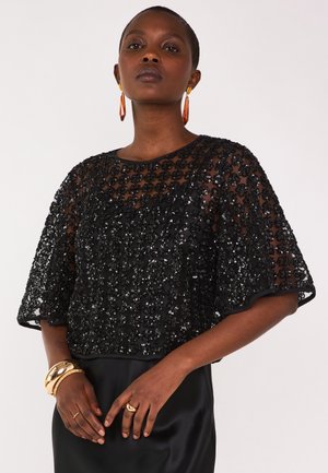 Black sequined top with short sleeves, featuring an intricate floral pattern. Smooth satin skirt with a fitted silhouette. Gold accessories included.