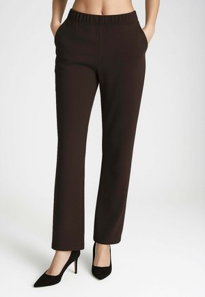 Pantaloni dritti di colore marrone scuro con cintura elastica e tasche laterali, abbinati a scarpe nere con tacco alto. Tessuto morbido.