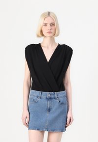 Body negro ajustado con mangas cortas, combinado con una mini falda de mezclilla azul claro, que cuenta con bolsillos y cierre de botones.