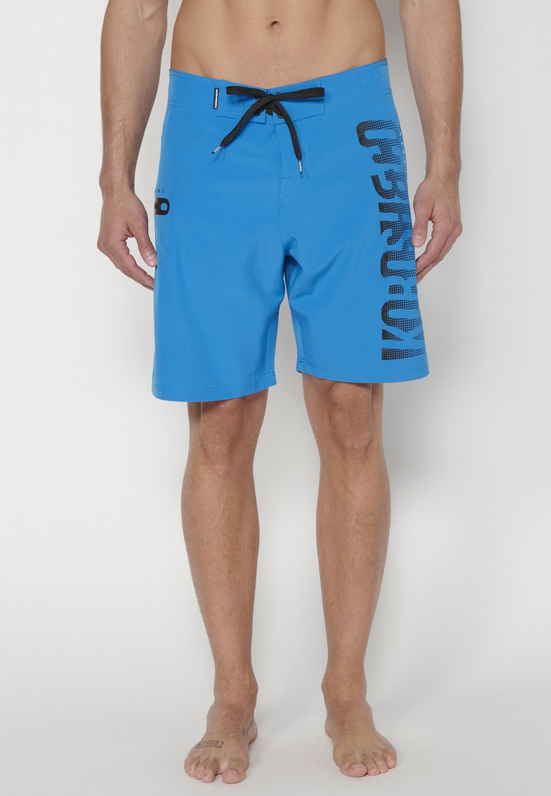Bañador azul con detalles en negro, con una cintura ajustable mediante cordón y un gran logo impreso en el lateral. Tejido suave y ligero.