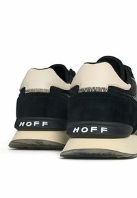 Zapatillas de ante y cuero negras con acentos crema y una suela beige. Presentan el logo de HOFF en el talón, detalles texturizados y un diseño elegante.