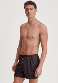 Marineblauwe zwembroek met geometrisch patroon, elastische tailleband en trekkoord. Gemaakt van lichtgewicht, sneldrogend materiaal.