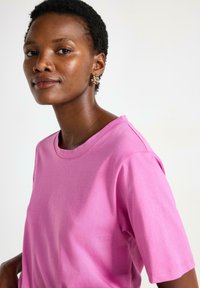 Pink bomulds T-shirt med korte ærmer og rund halsudskæring. Glat tekstur, basisdesign uden mønstre eller udsmykninger.