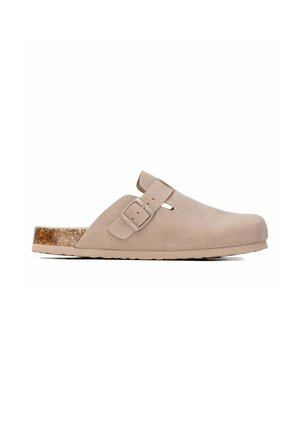 Zueco de ante beige claro sin cordones con hebilla lateral y tacón bajo con textura de corcho sobre fondo blanco.