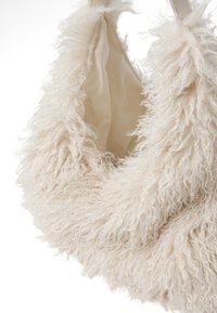 Borsa cremosa e fluffy con superficie testurizzata, realizzata in fibre morbide. Presenta un rivestimento interno liscio e doppie tracolle per il trasporto.