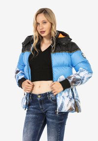 Daunenjacke mit einem blauen und weißen Bergmuster, schwarzen Schultern und orangefarbenem Innenfutter; Reißverschluss und gestrickte Bündchen.