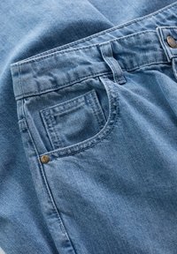 Light blue denim jeans with a classic pocket design, metal button closure, and visible stitching details. Soft texture and casual fit.