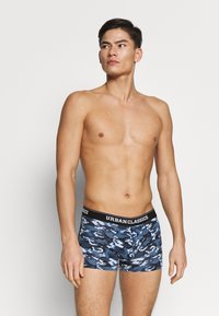 Navyblaue Camo-Boxershorts mit schwarzem elastischem Bund, der mit "URBANCLASSICS" beschriftet ist. Das weiche, dehnbare Material schmiegt sich eng an die Hüften.