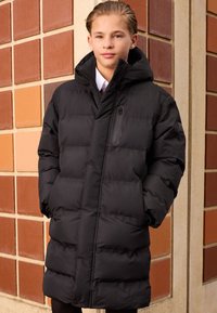 Veste matelassée noire avec fermeture éclair à l'avant, capuche et poches latérales. Présente une texture lisse et brillante ainsi qu'une silhouette ajustée et oversize.