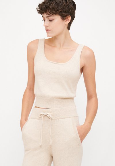 Μπεζ εφαρμοστό κορμάκι με φαρδύ λαιμόκοψη και ριμπ τελείωμα, συνδυασμένο με αντίστοιχο παντελόνι φόρμας με κορδόνι και πλαϊνές τσέπες. Μαλακή υφή.
