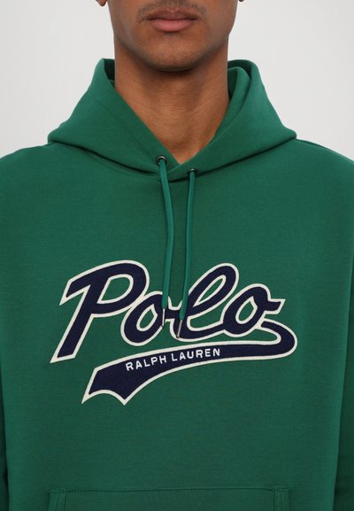 Felpa verde in tessuto morbido con un grande logo "Polo" in blu navy e dettagli bianchi. Ha un cappuccio con coulisse e una tasca anteriore.