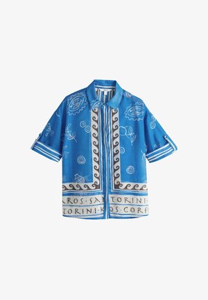 Chemise bleue à manches courtes avec col, motifs ondulés blancs et noirs, dessins botaniques et en spirale blancs, et texte faisant référence aux îles grecques.