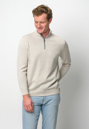 Helles beige Sweatshirt mit Reißverschluss am Hals, langen Ärmeln, gerippten Bündchen und Saum, aus weichem Stoff gefertigt. Der Reißverschluss ist grau und setzt einen dezenten Akzent.