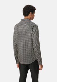 Langarmshirt in zwart-wit geometrisch patter, met een button-down kraag en een relaxte pasvorm, gemaakt van lichtgewicht stof.