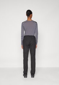 Sorte utendørsbukser med rett ben-design, med belte og sømdetaljer på knærne. Kombinert med en langermet grå topp.