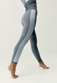 Szare legginsy sportowe z teksturowanym splotem, z barwnymi panelami w jaśniejszych odcieniach oraz wysokim stanem.