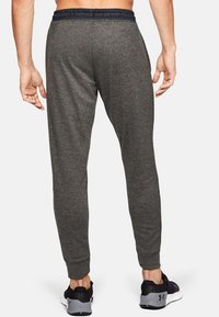Grijze sportbroek met een taps toelopende pasvorm, elastische tailleband en een gestreepte stof. Heeft een glad oppervlak en minimale details.