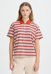 Polo à rayures aux teintes crème, rouge et bleu avec un col orange. Manches courtes et patte de boutonnage. Matière en coton doux.