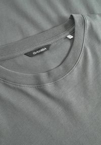 Szürke, puha pamutból készült póló, környakkal. A nyaknál GABBA címke és finom varrási részletek találhatók. Simap felületű.