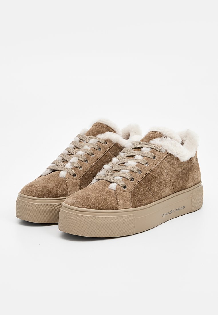 Beige Wildledersneaker mit einer dicken Plateausohle, weißem Schnürverschluss und weichem Futteram Kragen. Glatte Oberfläche und minimalistische Markenkennzeichnung.