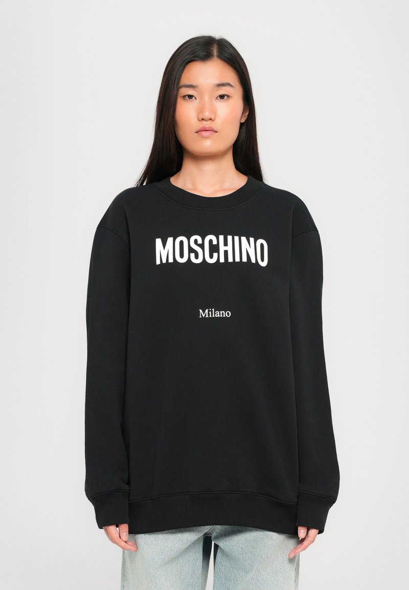 Sudadera negra con el logo blanco de "MOSCHINO" y el texto "Milano" debajo. Cuenta con un cuello redondo, mangas largas y puños y dobladillo acanalados.