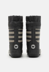 Botas de goma negras con un acabado texturizado, presentan rayas grises verticales y un logotipo circular en la parte posterior. Puños ligeramente acampanados en la parte superior.