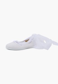 White ballet flat with a textured surface and a sheer white ribbon tied at the back, set against a plain white background.