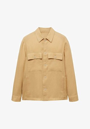 Beige liinajakk klassikalise kraega, kahe rinna-taskuga ja ees asuva nupuga sulgemisega. Omab pikki varrukaid ja sirget lõiget.