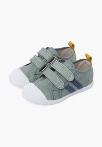 Scarpe da ginnastica verdi in tela con suole bianche in gomma, due cinturini regolabili, dettagli blu navy e un'etichetta gialla sul tallone per una facile vestibilità.