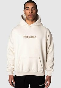 Cremefarbener Hoodie mit einer Vordertasche und dem Text "DROP SIZE" in Gold. Verfügt über eine Kapuze mit Kordelzug sowie gerippte Bündchen und Saum. Weicher Stoff.