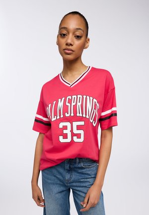 Maglietta in cotone rossa con scollatura a V, caratterizzata da "PALM SPRINGS" e dal numero "35" in bianco, con strisce bianche e nere sulle maniche.