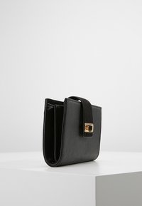 Black leather wallet with a folded design, adorned with a gold rectangular clasp. Smooth texture, compact shape, no visible patterns.