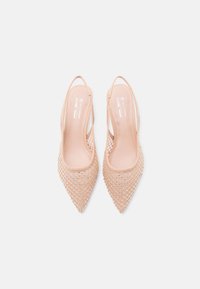 Μπεζ μυτερά φλατ παπούτσια slingback με επικάλυψη από δίχτυ και μικρές μεταλλικές τρουκς, με ετικέτα vegan και την επωνυμία "Call it Spring."