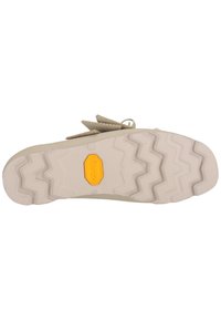 Semelle de chaussure beige avec motif de bande de roulement en zigzag et logo Vibram jaune au centre, vue du dessous.
