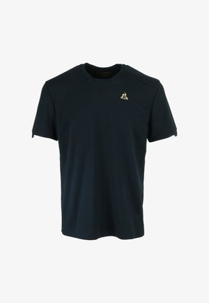 T-shirt en coton bleu marine foncé avec des manches courtes, un col rond et un petit logo doré sur la poitrine gauche. Texture lisse.