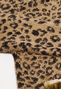 Țesătură cu imprimeu de leopard, având o bază maro deschis cu pete negre mai închise, textură moale și o mică bordură decorativă cu perle și blană verde.