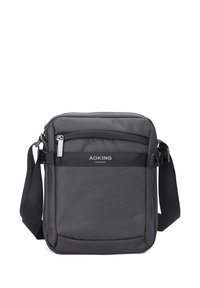 Borsa a tracolla nera con superficie texturizzata, scomparti con zip, tracolla regolabile e etichetta con logo sul davanti. Forma rettangolare compatta.