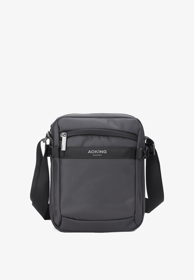 Borsa a tracolla nera con superficie texturizzata, scomparti con zip, tracolla regolabile e etichetta con logo sul davanti. Forma rettangolare compatta.