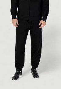 Schwarze Zip-Hoodie mit Fronttaschen und passenden schwarzen Jogginghosen; bietet eine schmale Passform, gerippte Bündchen und dezente Markenkennzeichnung an der Seite.
