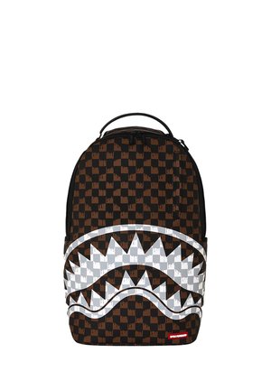 Mochila con patrón de cuadros negro y marrón y gran gráfico blanco de boca de tiburón en el bolsillo delantero.