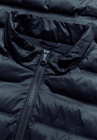 Schwarze, wattierte Jacke mit hohem Kragen, ausgestattet mit einem zentralen Reißverschluss und glatter, glänzender Oberfläche. Gestepptes Design mit horizontalen Abschnitten.