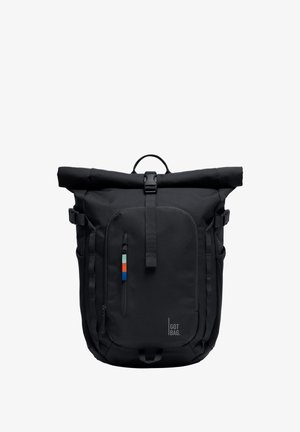 Zaino nero con chiusura roll-top, tasca frontale con zip, fibbia sulla tracolla, cinghie di compressione laterali e una piccola etichetta colorata sul tirazip.