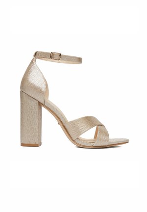 Goldfarbene, strukturierte Sandale mit Blockabsatz, Knöchelriemen mit Schnalle und sich kreuzenden Riemen über dem offenen Zehenbereich.